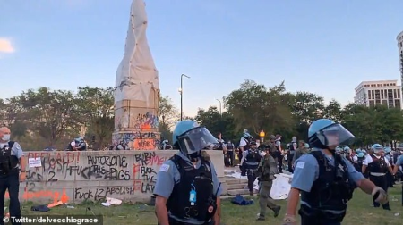 Two police officers in front of graffitied monument