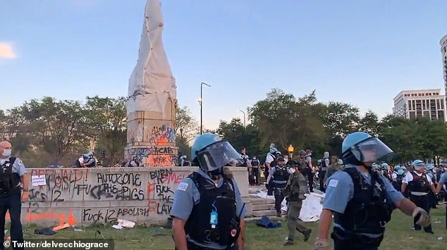 Two police officers in front of graffitied monument