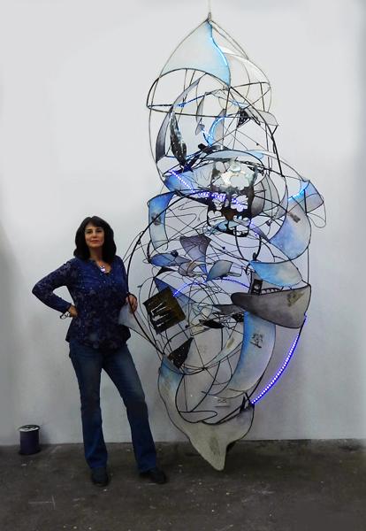 Jill King beside a wall mounted sculpture made from metal and fabric